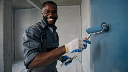 positive african american master paints wall, apartment renovation