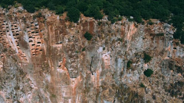 Remains of an ancient Lycian rock necropolis in the city of Pinara in Turkey. A rock with carved tombs. Lycian rock tombs overlooking the ancient Lycian city of Pinara from the air. Drone. 4К