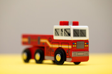 a wooden firetruck on beige and yellow background 