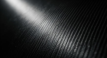 Close up view of dark carbon fiber texture with reflective light highlight
