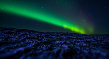 Spectacular green northern lights aurora borealis illuminate dark starry night sky over textured ground