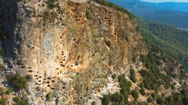 Remains of an ancient Lycian rock necropolis in the city of Pinara in Turkey. A rock with carved tombs. Lycian rock tombs overlooking the ancient Lycian city of Pinara from the air. Drone. 4К