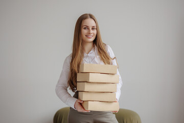 Young woman holds stacked boxes in modern indoor space, displaying confidence and organization...