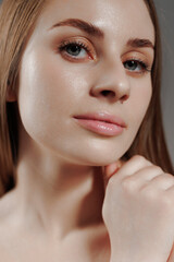 Obraz premium Close-up of a woman showcasing smooth skin and natural makeup under soft lighting in a studio setting during an artistic portrait session