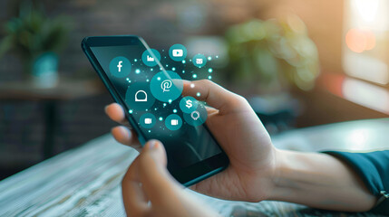 A person holding a smartphone displaying social media icons with a blurred background indoors setting
