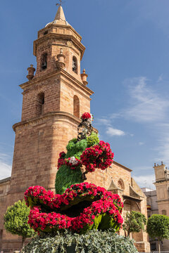 Andujar, Jaen Province, Andalusia, Spain. Red flowers and the bell tower of the San Miguel Church.