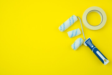 Paint roller on yellow background, right side, top view