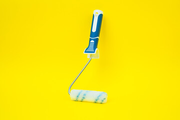 Paint roller on yellow background, vertical, centered