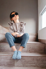 Preteen Posing Thoughtfully on Wooden Steps with oversized Sunglasses