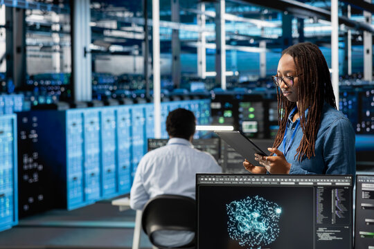 Data center programmer uses AI visualization tool on tablet to optimize resource allocation. Server hub IT professional uses artificial intelligence analysis on device to do maintenance