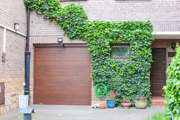 Modern Brick House Exterior with Wooden Garage Door and Green Ivy Climbing the Wall
