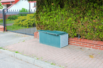 Blue Metal Security Box Near Entrance Gate with Metal Fence and Brick Base in Residential Area