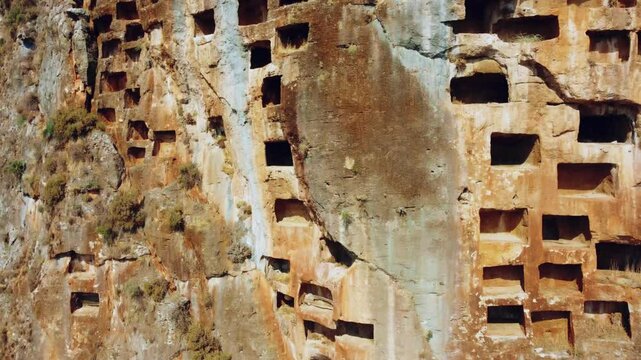 Remains of an ancient Lycian rock necropolis in the city of Pinara in Turkey. A rock with carved tombs. Lycian rock tombs overlooking the ancient Lycian city of Pinara from the air. Drone. 4К