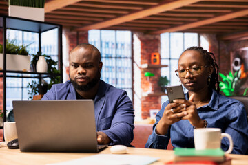 Black couple at their home office working remotely on daily tasks, networking with clients, managing remote work tasks and strategizing ways to improve their online startup business.