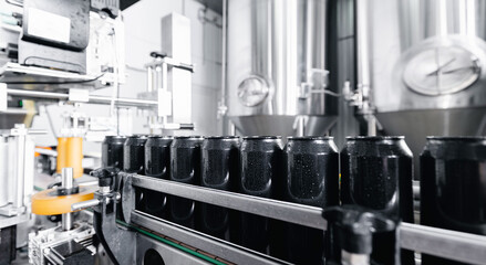Industrial beer production line with rows of black cans in brewery factory