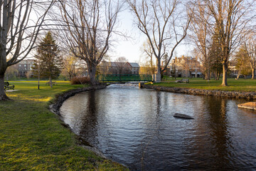 Fototapeta premium A small footbridge over a creek in spring. Stewart Park In Perth, Ontario, Canada