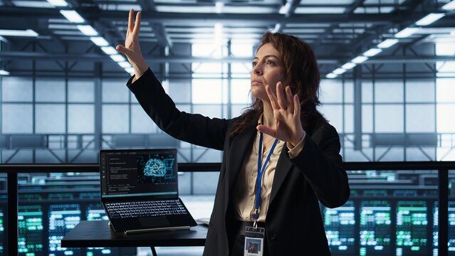 Technicians in high tech AI data center workspace looking at hologram visualization. Programmer working on securing server room hardware using AR artificial intelligence tech, camera B