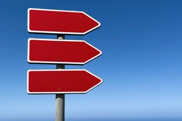 Three blank red directional signs against a clear blue sky
