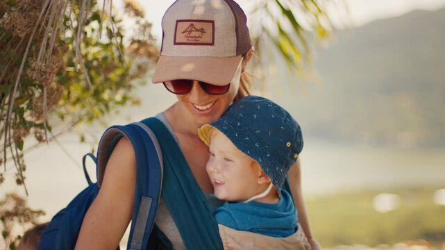 Family hiking. Woman takes selfie with kid sitting in baby carrier