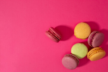 Colorful macaroons cakes on pink background. Flat lay.