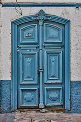 Blue wooden door with intricate carvings and vintage details, framed by textured white walls and blue accents, showcasing architectural beauty and cultural heritage in Cuenca Ecuador Latin America
