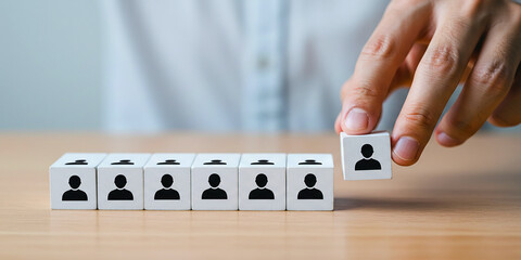 Hand selecting standout candidate from row of team member blocks showing talent acquisition concept