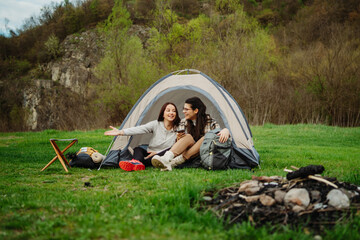 Two female friends setting up camp in the forest after hiking or trekking