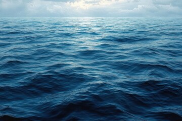Fototapeta premium Vast calm ocean under a partly cloudy sky with gentle waves reflecting soft sunlight