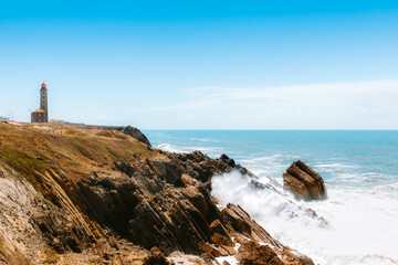 Sao Pedro de Moel Lighthouse (Farol do Penedo da Saudade) standing on rocky coast of Leiria, Portugal