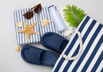 Blue beach bag with summer accessories on color background, top view