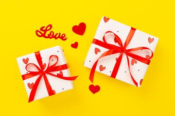 Festive gift boxes with red hearts on color background, top view
