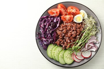 Tasty salad with brown rice on white wooden table, top view