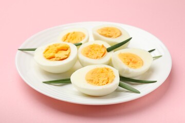 Boiled eggs and green onions on pink background, closeup