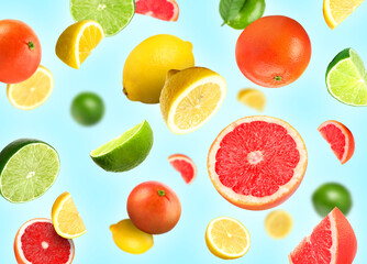 Different fresh citrus fruits in air on light blue background