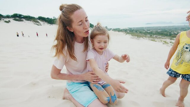Family sandboarding. Girls cry after crash on the sand dune