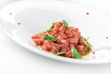 Tartar with tuna, avocado and sauce decorated with cilantro on plate isolated on white background....
