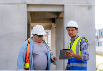 Two engineers holding tablets checking and planning work in construction project. Teamwork concept.