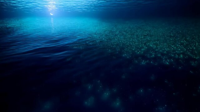 Ocean with bioluminescent organisms creating turquoise light patterns on dark sea water surface, underwater scene