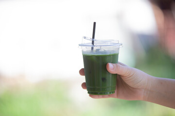 hand holding a glass of green tea