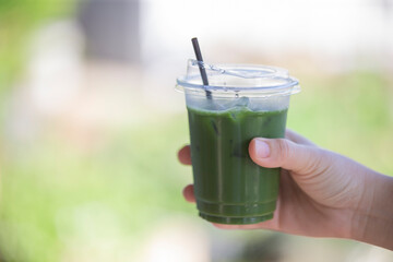 hand holding a glass of green tea