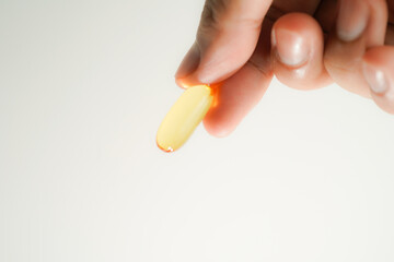 Male hand holding Fish oil capsules with omega 3, omega 9, vitamin D, vitamin E, Cod liver oil