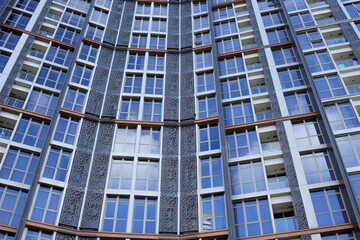 Low Angle View Of Modern High-Rise Apartment Building With Numerous Windows Reflecting The Sky