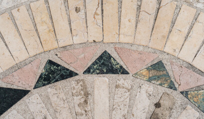 Diseño geométrico de mosaico en piedra natural sobre superficie de concreto