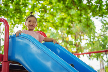 happy toddler baby girl sliding and playing at playground