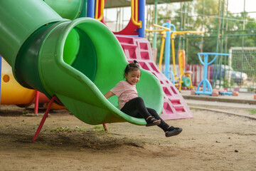 happy toddler baby girl sliding and playing at playground