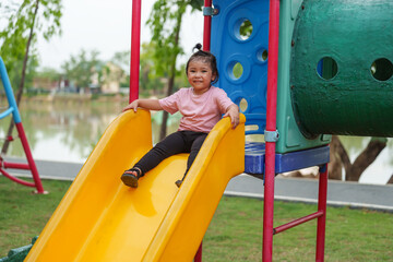happy toddler baby girl sliding and playing at playground