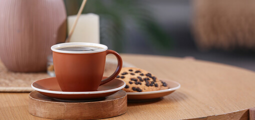 Cup of hot coffee and tasty cookies on wooden table in room