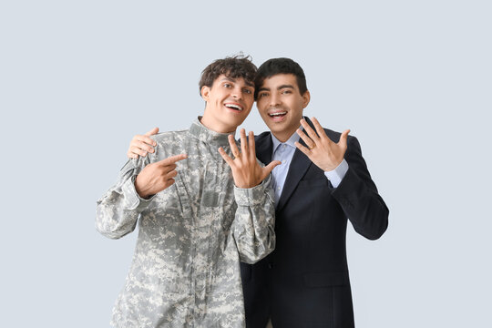 Young soldier with his husband on light background