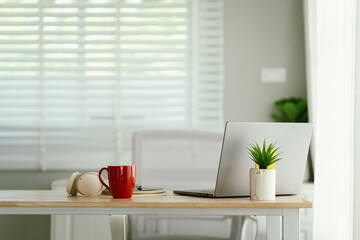 Obraz premium A modern, minimalist desk workspace with a laptop, headphones, notepad, cup of coffee, and houseplant, ready for productive remote work.