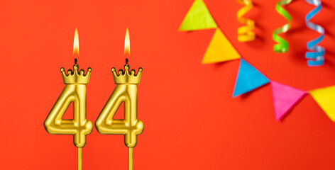 Number 44 birthday candle on an orange background with pennants